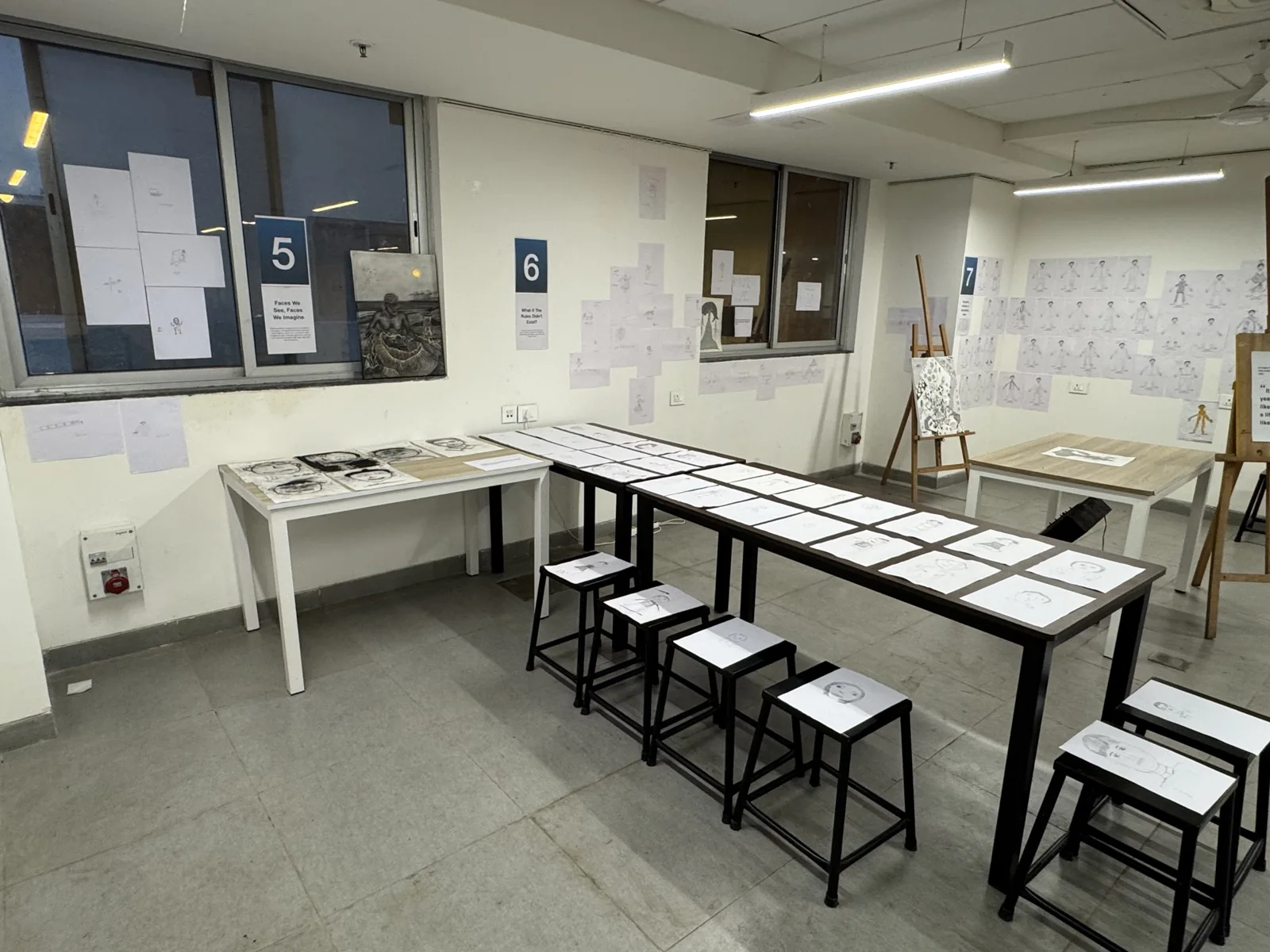 Exhibition tables and stools surrounded by drawing displays