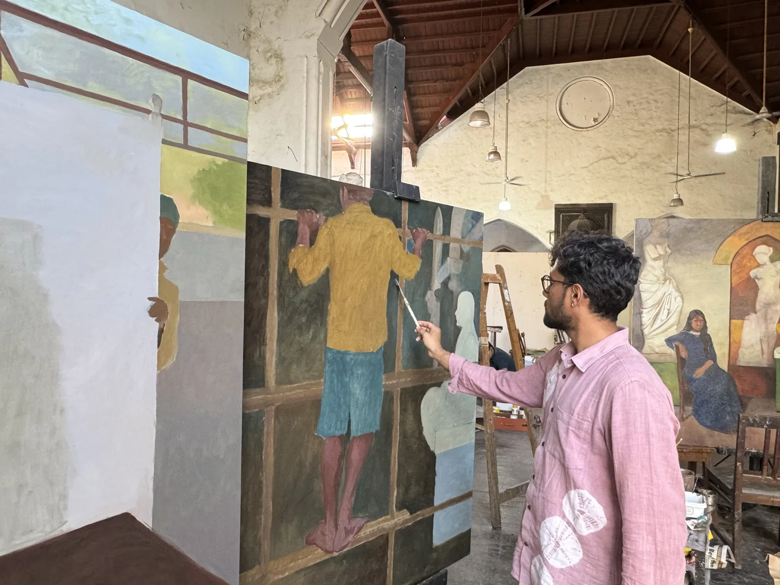 A person gesturing toward a large painting in an art studio