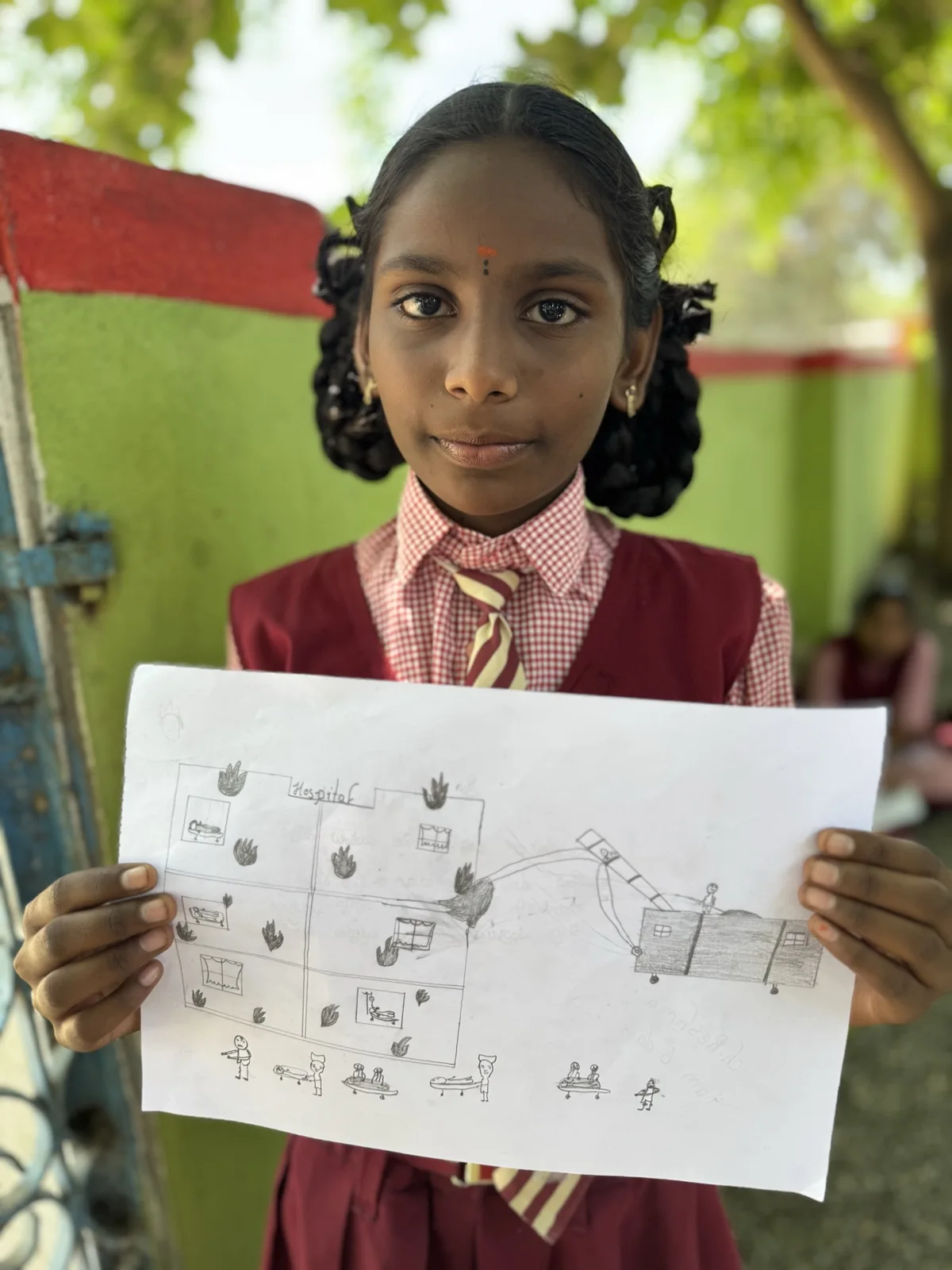 A child holding a pencil drawing with several figures and scenes